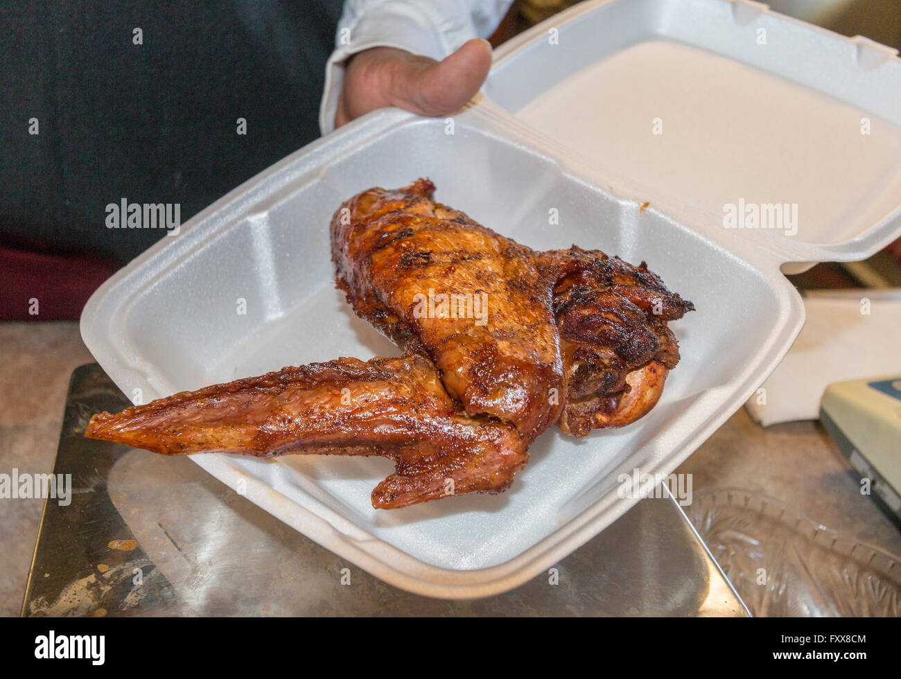 Darby Guillory hält einer der seinen riesigen, eine frisch zubereitete BBQ Türkei Flügel. Stockfoto