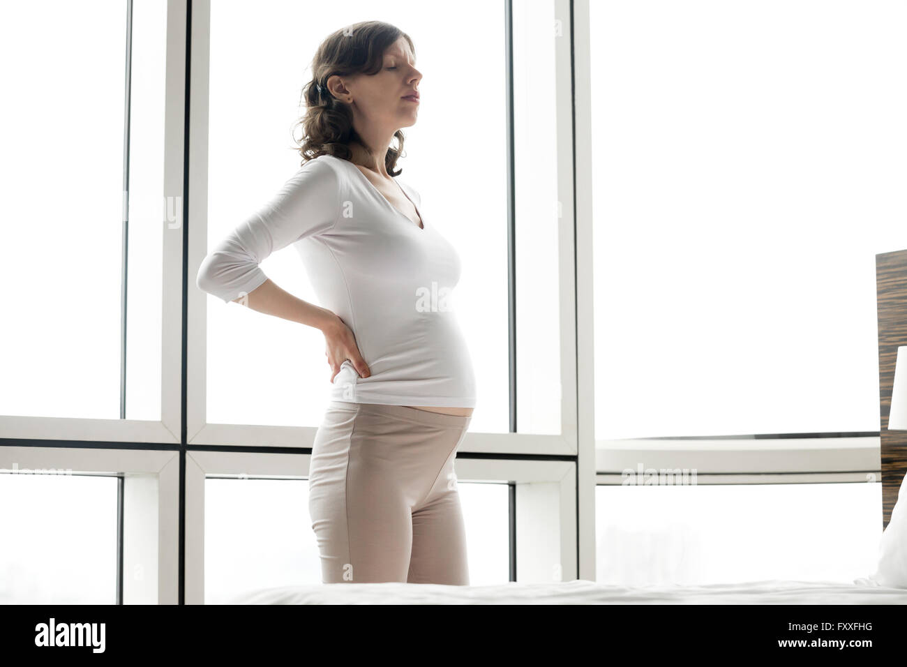 Healthcare, Behandlung. Junge schwangere unglückliche Gefühl plötzlicher Schmerz im Rücken. Zukünftige Mama leiden unter Rückenschmerzen Stockfoto