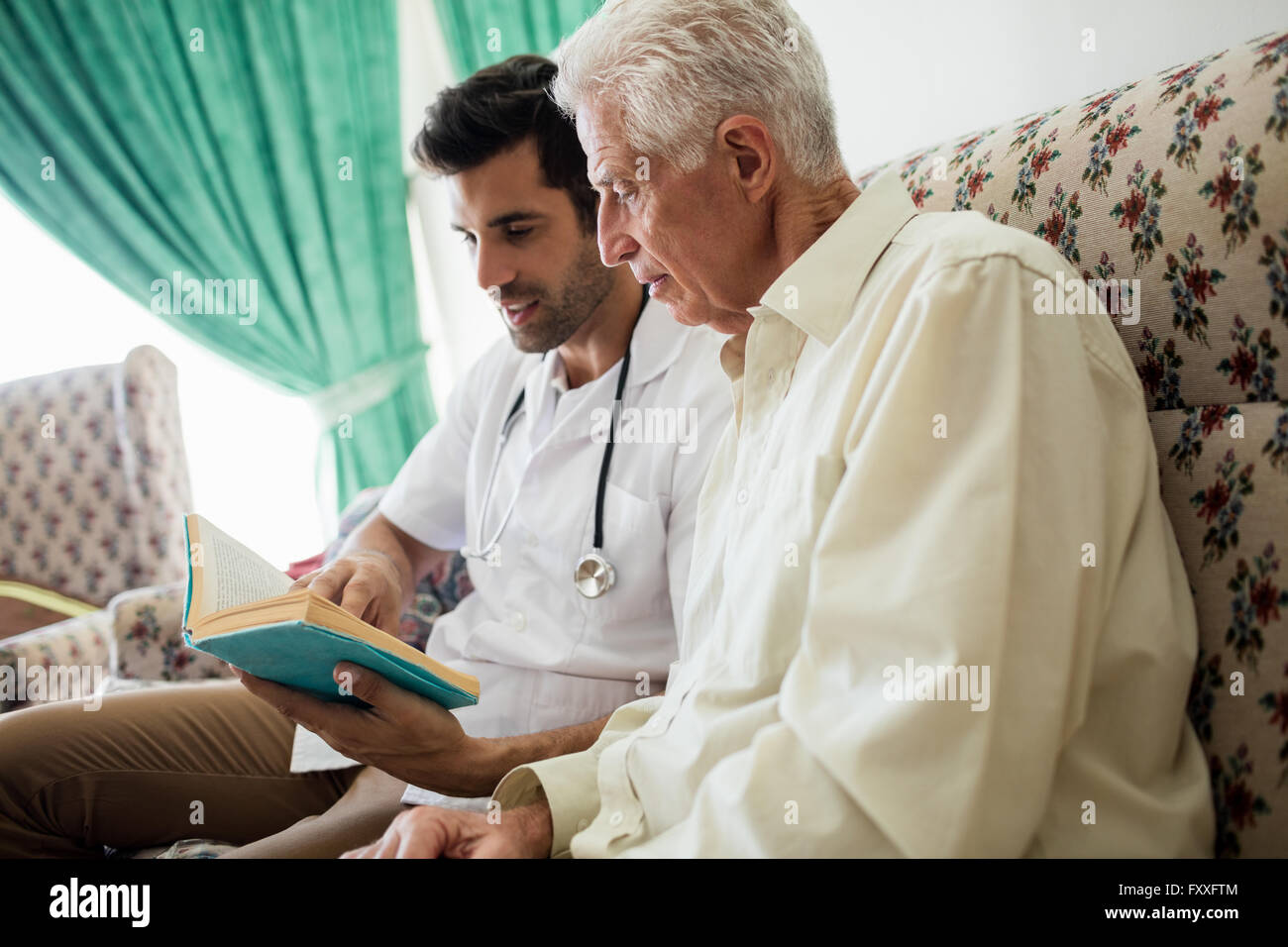 Krankenschwester und Senior Mann liest ein Buch Stockfoto