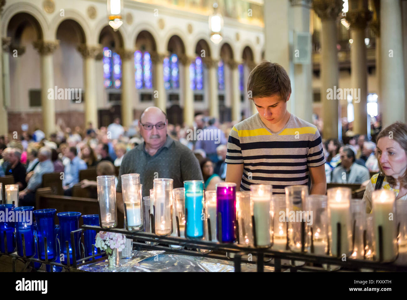 Detroit, Michigan - ein junger Mann zündet eine votive Kerze vor Beginn der Messe in der Erlöser, Heilige, katholische Kirche. Stockfoto