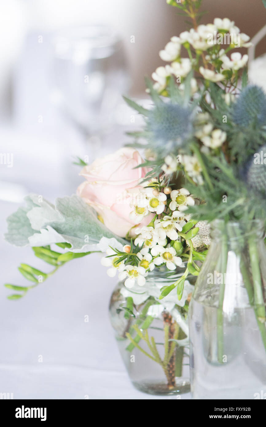 Tisch für Hochzeit oder Veranstaltung mit informellen Blumenarrangements in Vintage-Flaschen Stockfoto