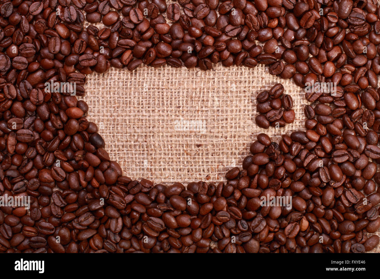 Geröstete Kaffeebohnen mit textfreiraum in Form eines Bechers auf Sackleinen Hintergrund Stockfoto