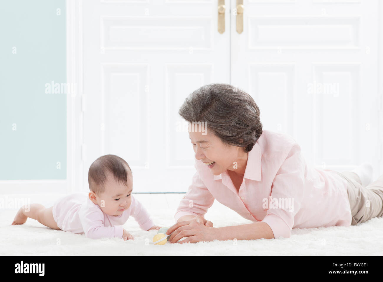 Ältere Frau auf den Bauch auf dem Boden liegend und kümmert sich um ein baby Stockfoto