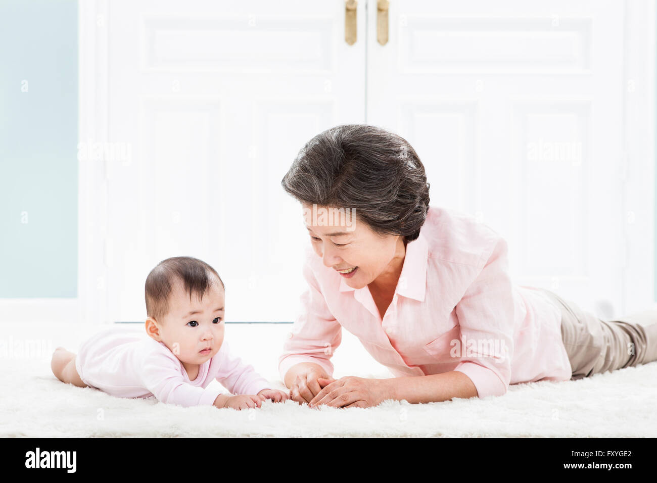 Ältere Frau auf den Bauch auf dem Boden liegend und kümmert sich um ein baby Stockfoto
