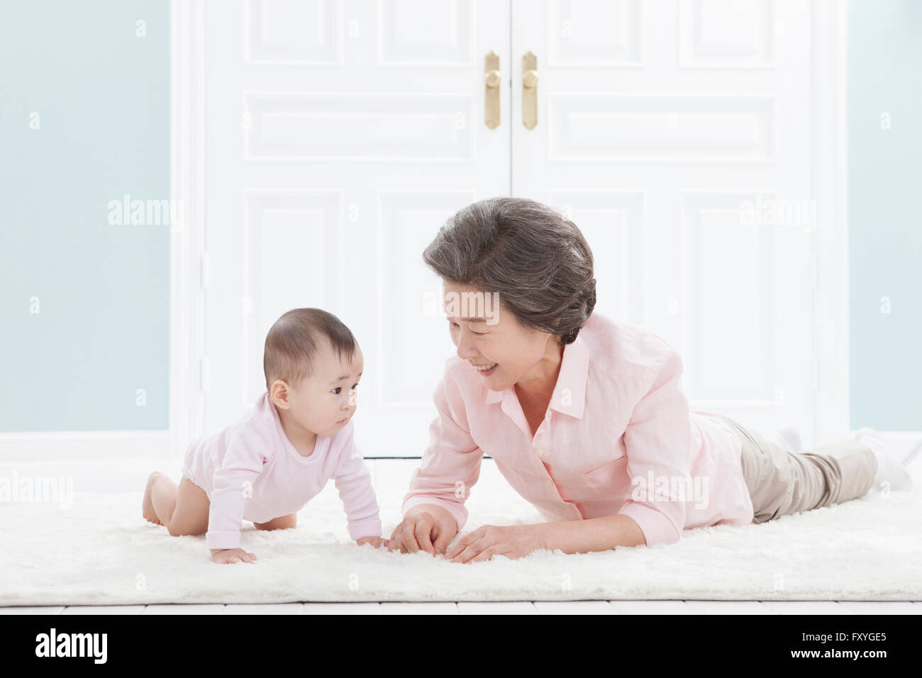 Ältere Frau auf den Bauch auf dem Boden liegend und kümmert sich um ein baby Stockfoto