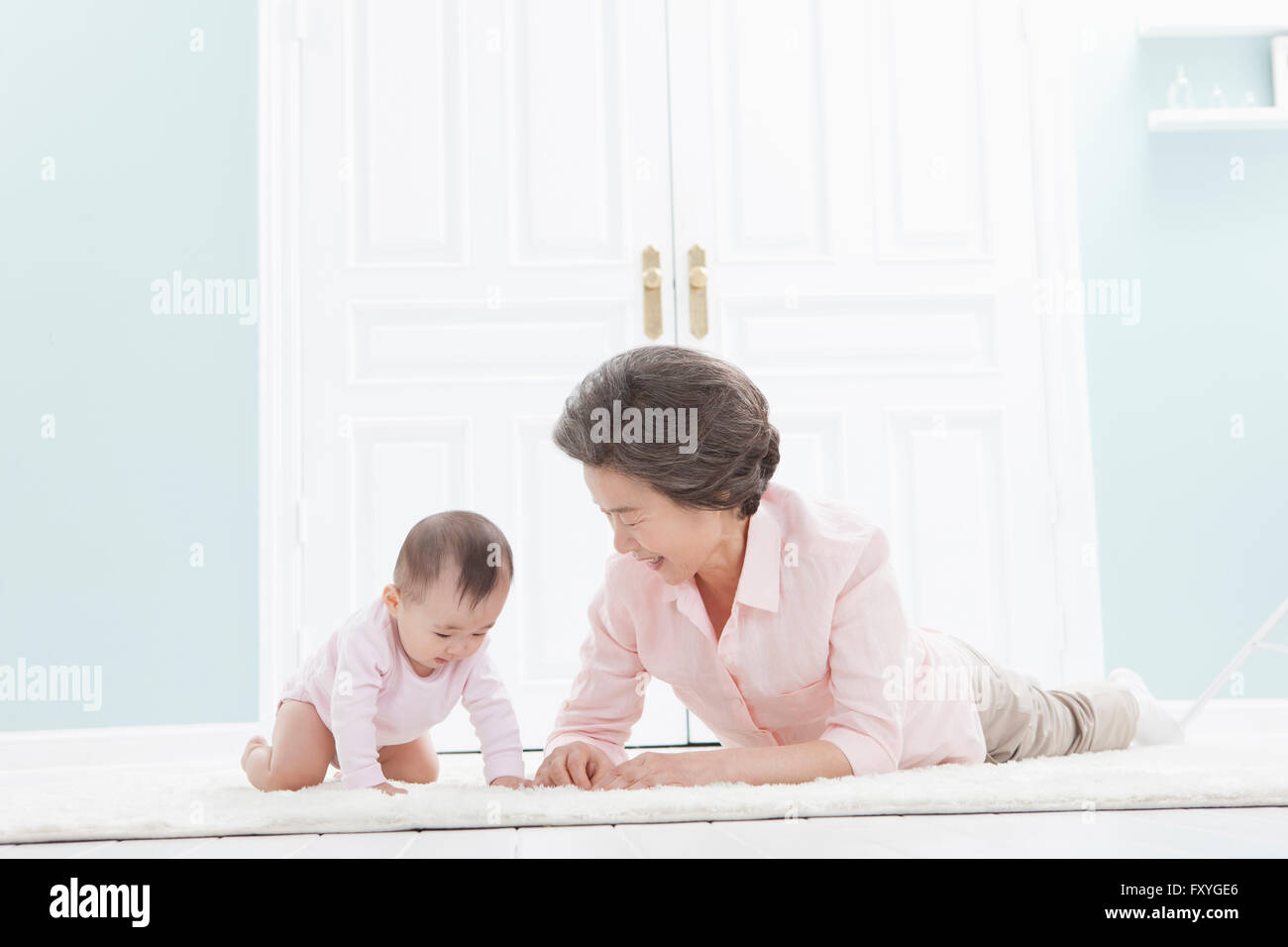 Ältere Frau auf den Bauch auf dem Boden liegend und kümmert sich um ein baby Stockfoto