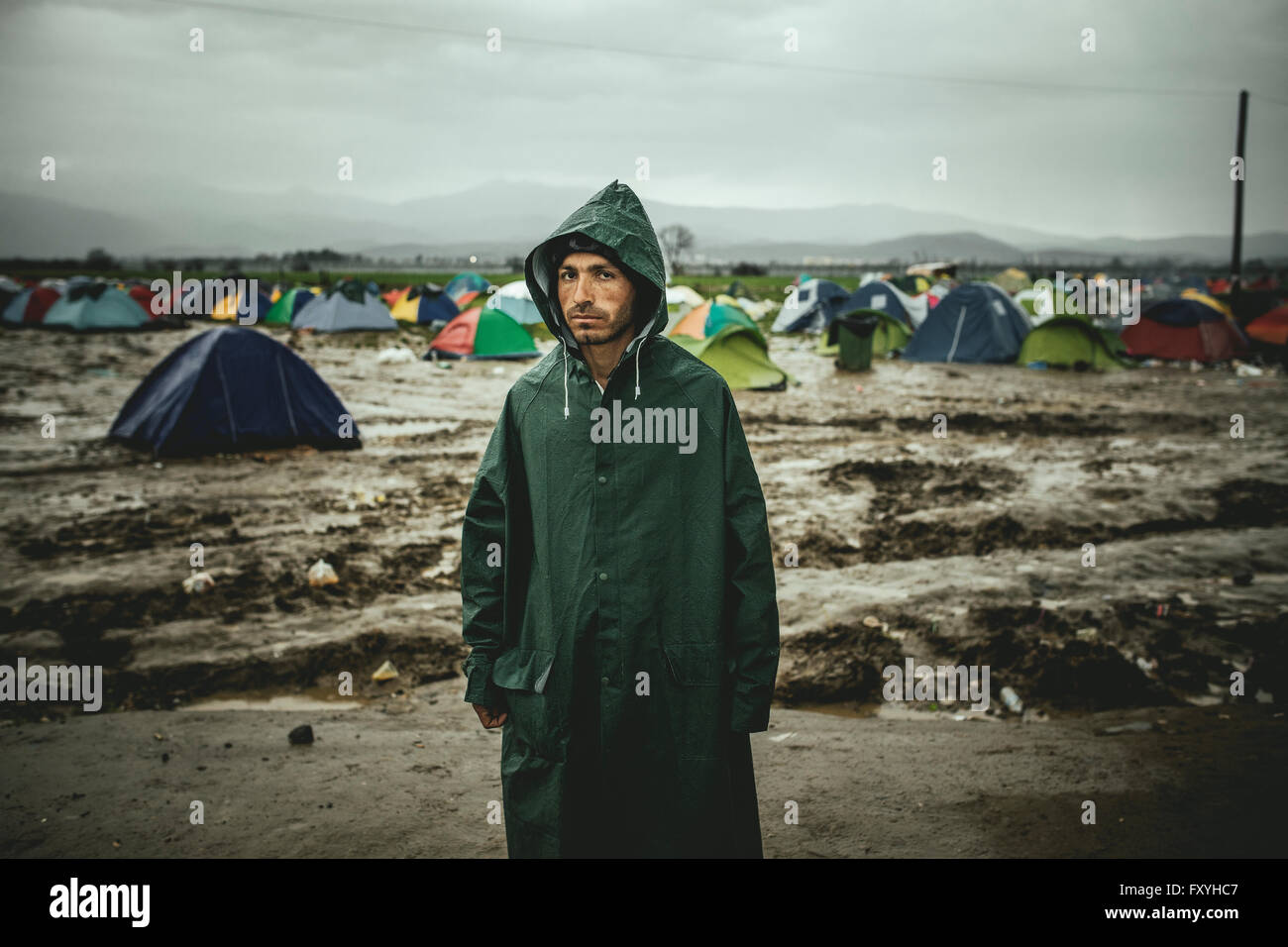 Mann wartet draußen Zelte bei starkem Regen, Flüchtlingslager in Idomeni, Grenze zu Mazedonien, Griechenland Stockfoto