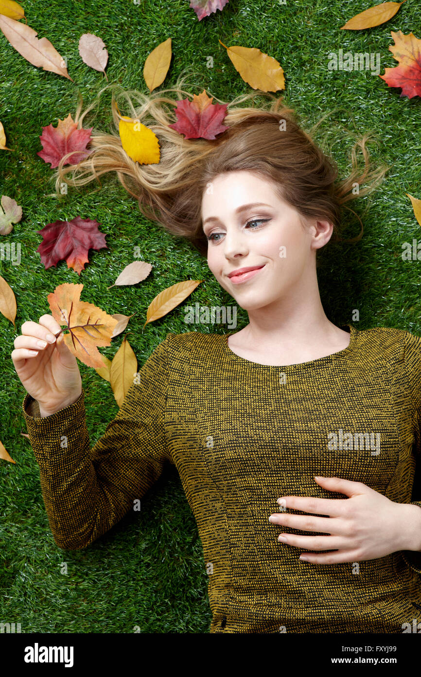 Hohen Winkel eine Frau liegt auf dem Rasen mit abgefallenen Blättern was Rückgang Stockfoto