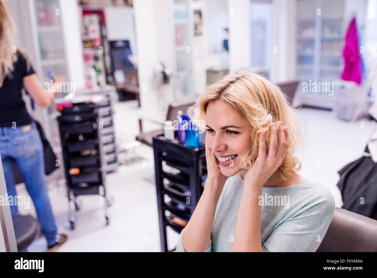 Junge, blonde Frau beim Friseursalon mit neuer Frisur Stockfoto