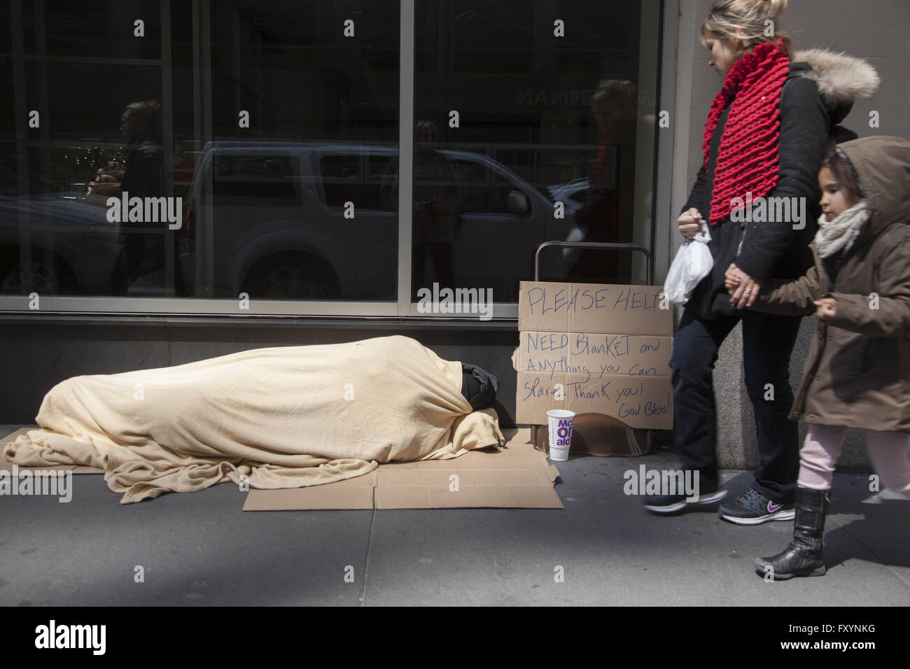 Obdachloser schläft auf dem Bürgersteig in Midtown Manhattan als Menschen vorbei. Stockfoto