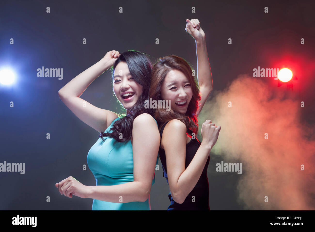 Seite Ansicht Portrait jungen lächelnde Frauen Rücken an Rücken tanzen im Nachtclub Stockfoto