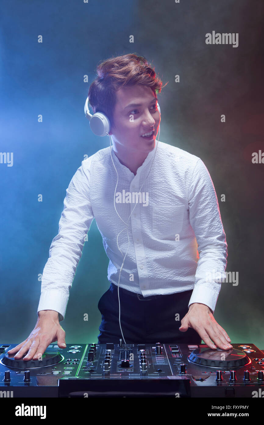DJ in den frühen Dreißigern im Nachtclub lächelnd Stockfoto