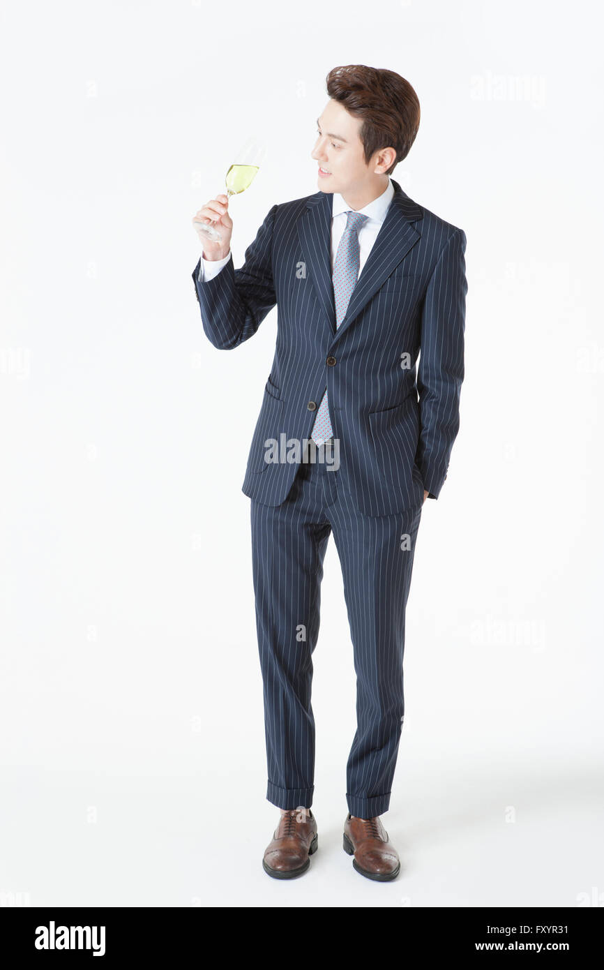 Junger lächelnder Mann in Anzug Stand mit einem Glas Champagner auf der Suche nach unten Stockfoto