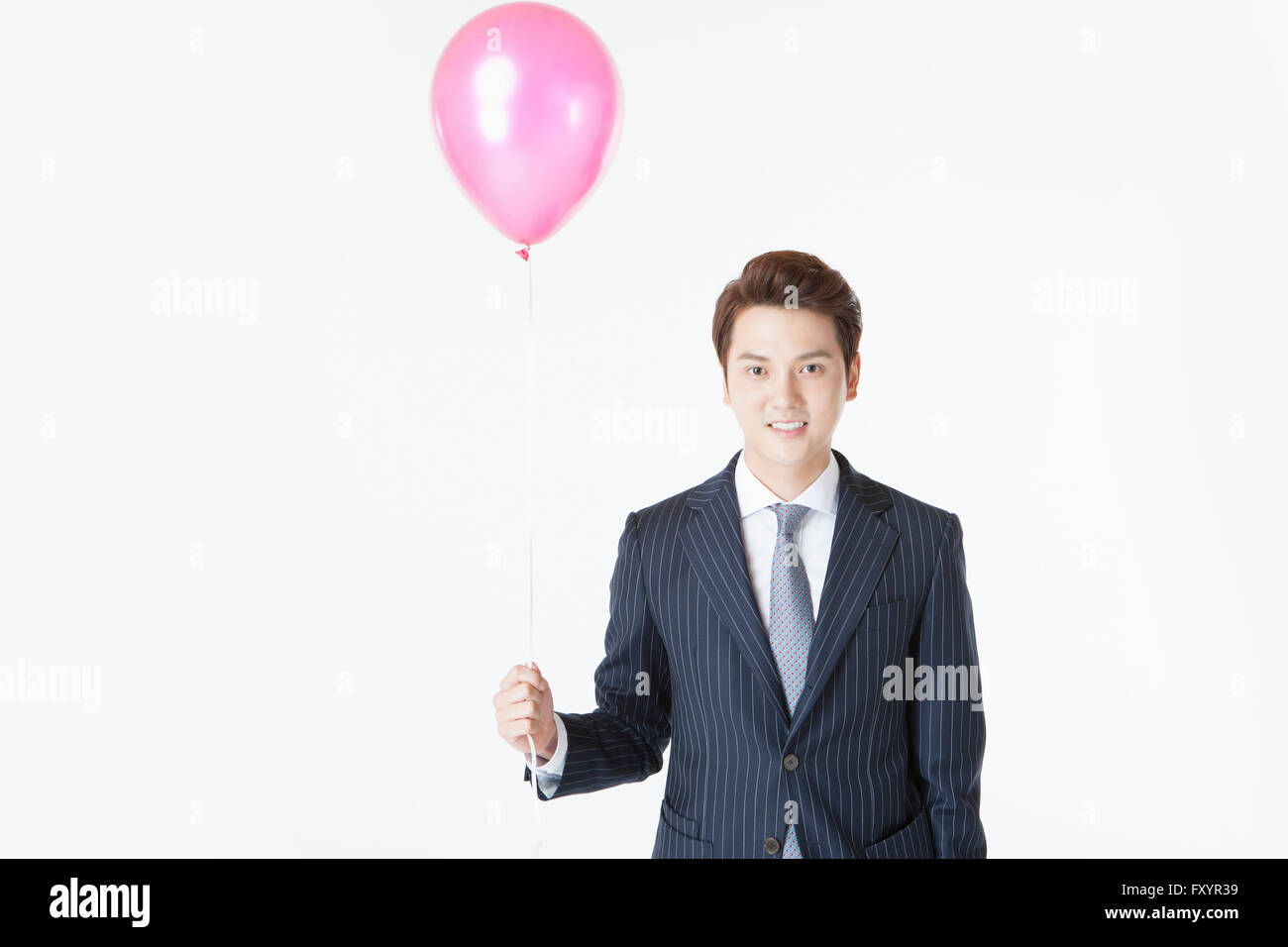 Porträt des jungen lächelnd Mann im Anzug hält Luftballons starrte auf Vorderseite Stockfoto