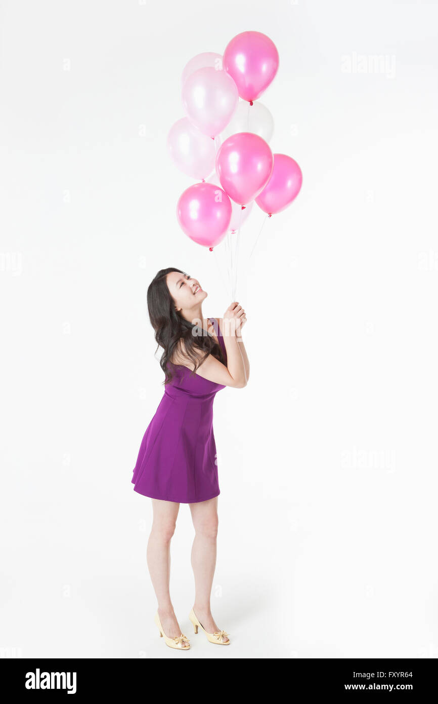 Seitenansicht des jungen lächelnde Frau mit Luftballons nachschlagen Stockfoto
