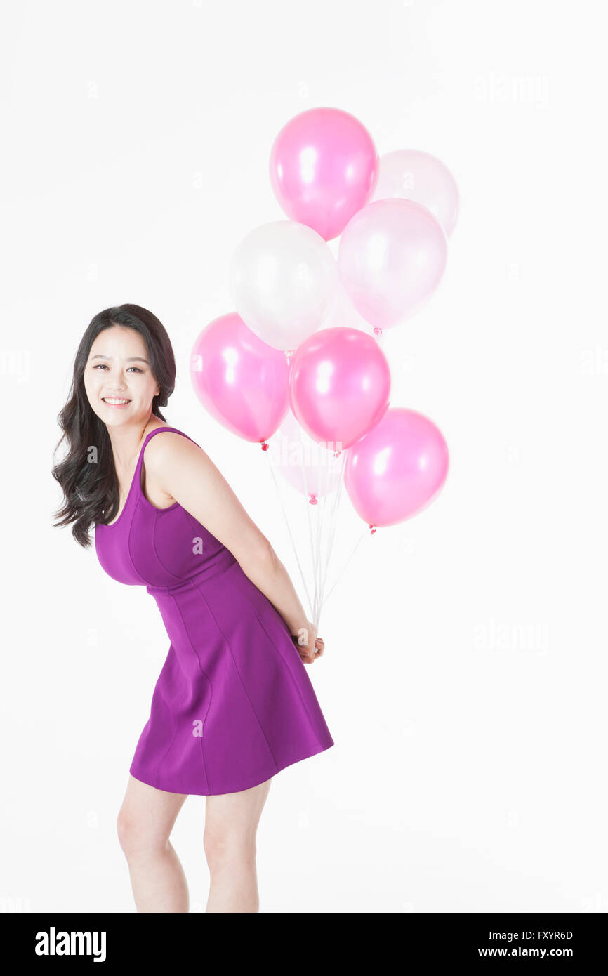 Seitenansicht des jungen lächelnde Frau posiert mit Ballons starrte auf Vorderseite Stockfoto