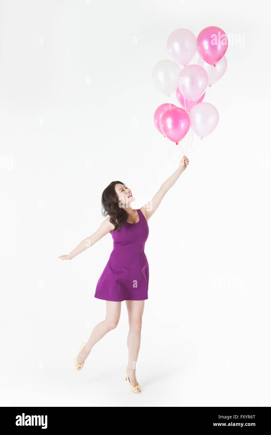 Seitenansicht des jungen lächelnde Frau hält ein Bündel von Ballons nachschlagen Stockfoto