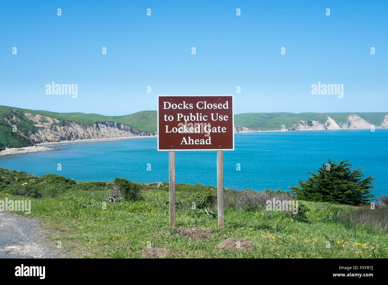 Am Meer Vista mit Felsen und grünen Hügeln mit einem braunen Schild, das liest, "Docks geschlossen zur öffentlichen Nutzung gesperrt Tor voraus" Stockfoto