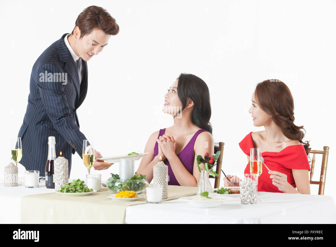 Seite Ansicht Porträt des jungen Mannes Essen für zwei junge Frauen, die am Tisch serviert Stockfoto