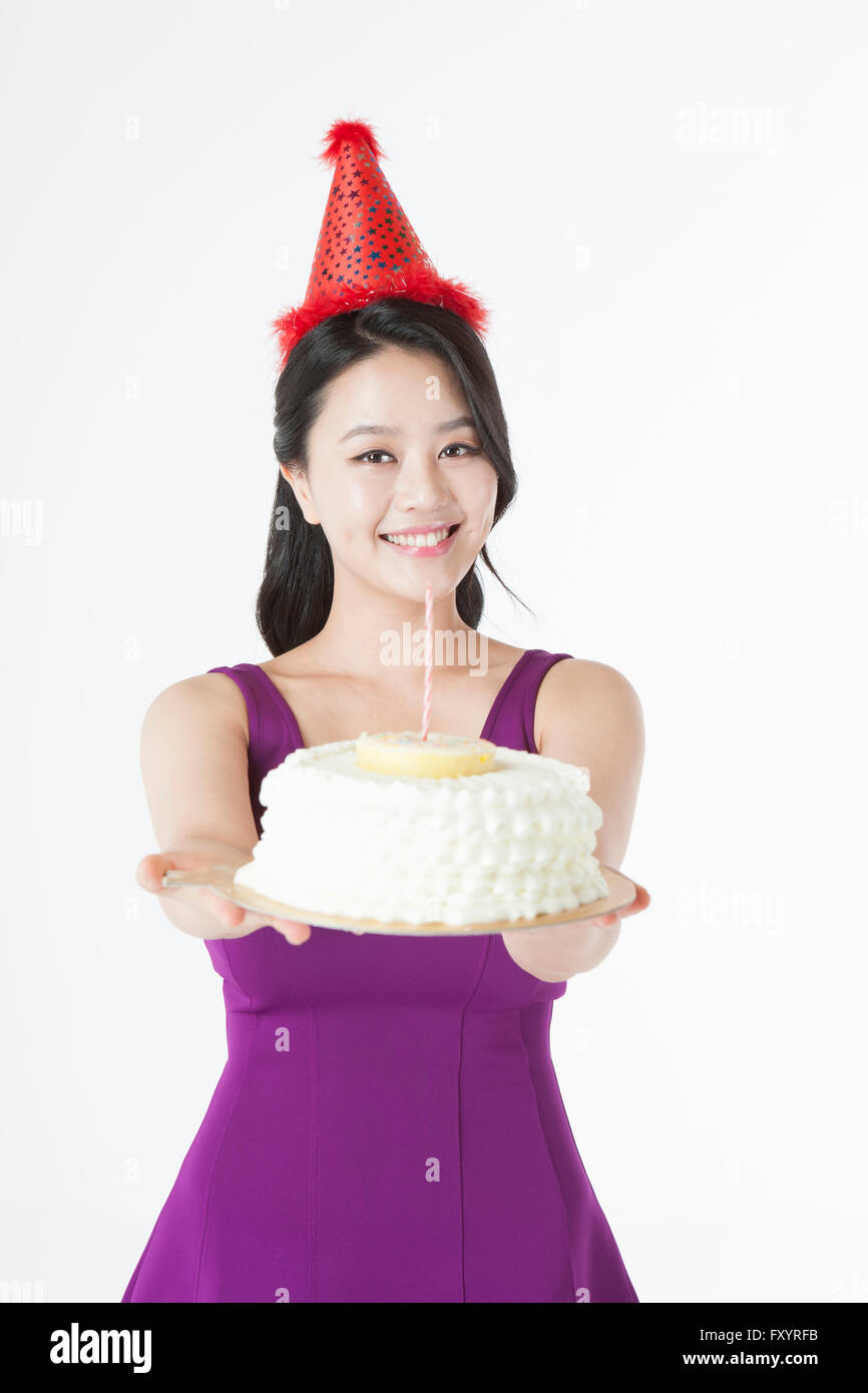 Porträt des jungen lächelnde Frau mit Partyhut hält einen Kuchen starrte auf Vorderseite Stockfoto