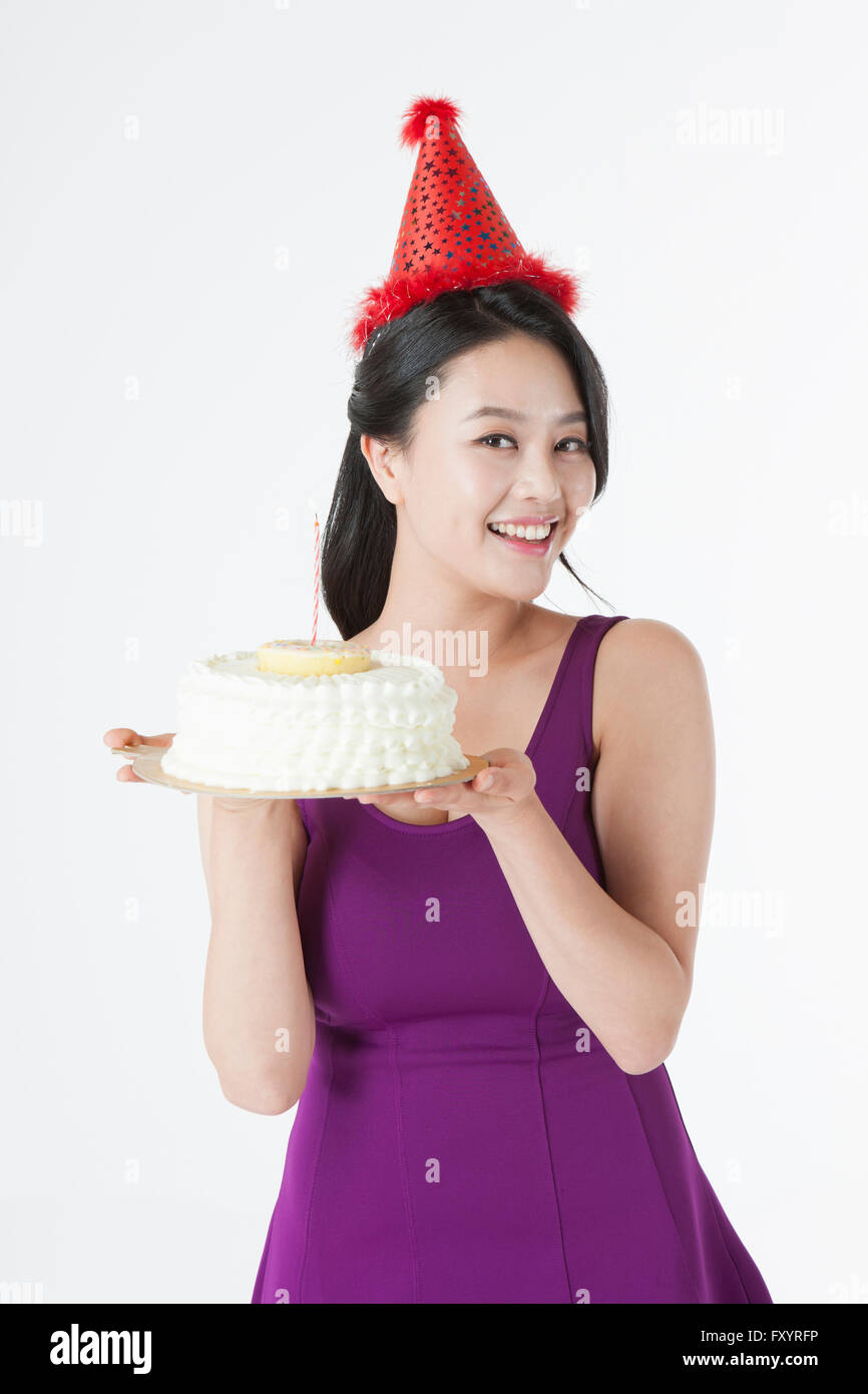 Porträt des jungen lächelnde Frau mit Partyhut zeigt einen Kuchen Stockfoto