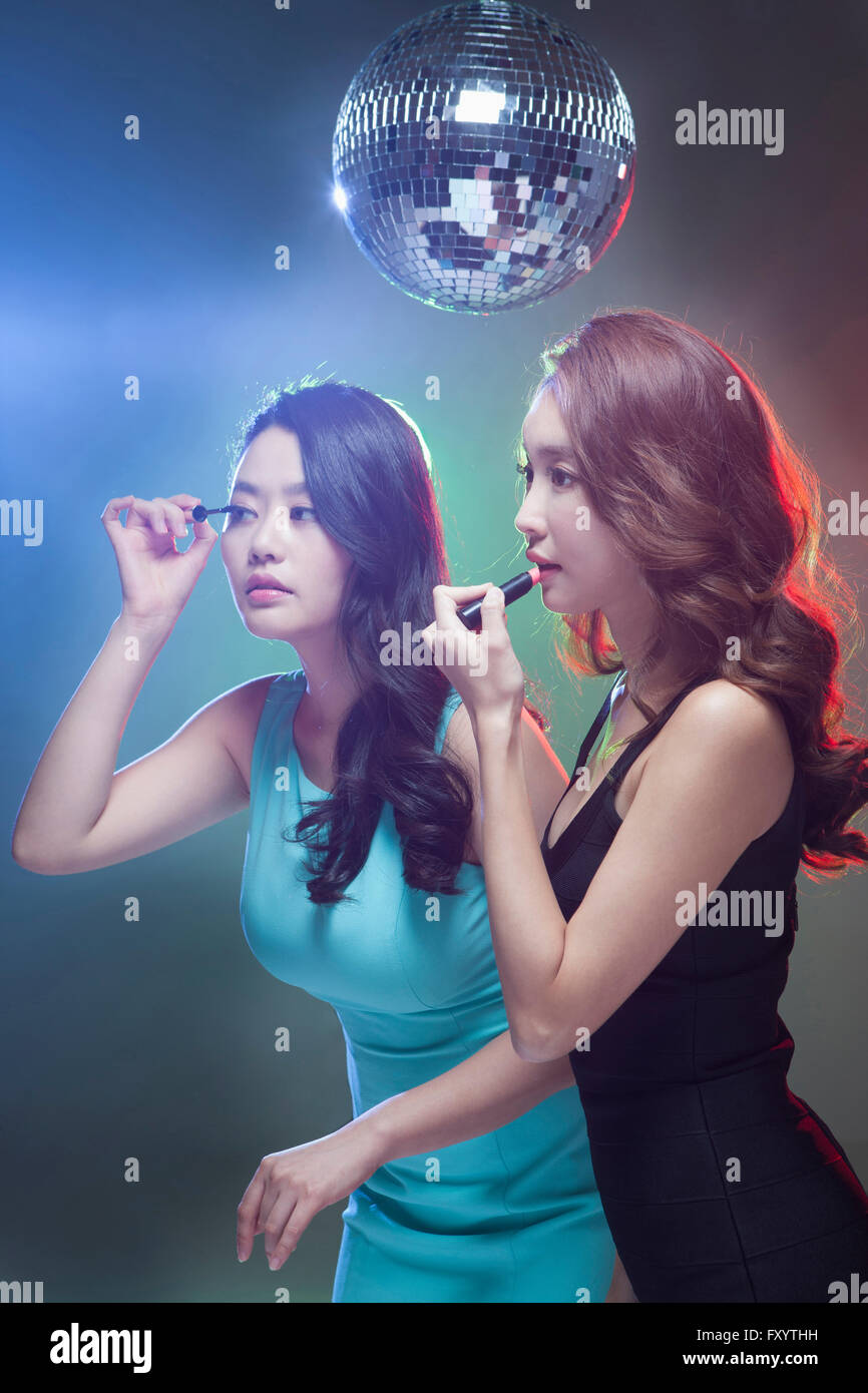 Seitenansicht von zwei jungen Frauen setzen auf Make-up unter eine Spiegelkugel Stockfoto