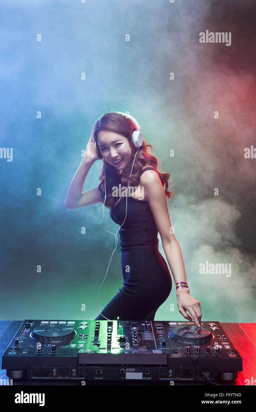 Seitenansicht der jungen weiblichen DJ spielt Musik vorne starrte lächelnd Stockfoto