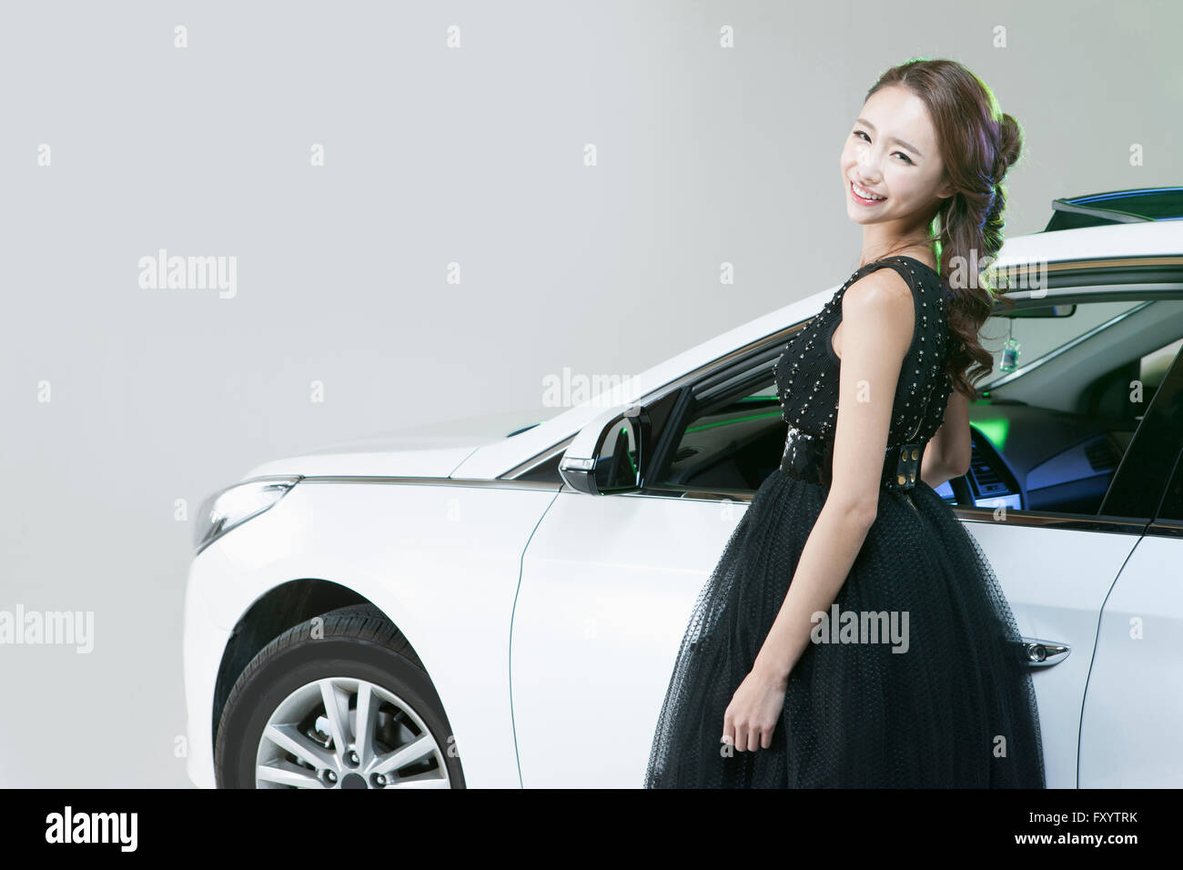 Seitenansicht der junge lächelnde Frau im Kleid gegen ein Auto starrte auf Vorderseite Stockfoto