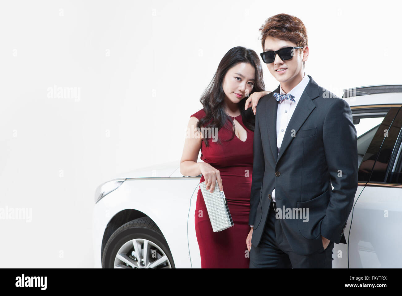 Junges Paar in Kleid und Anzug posiert vor einem Auto starrte auf Vorderseite Stockfoto