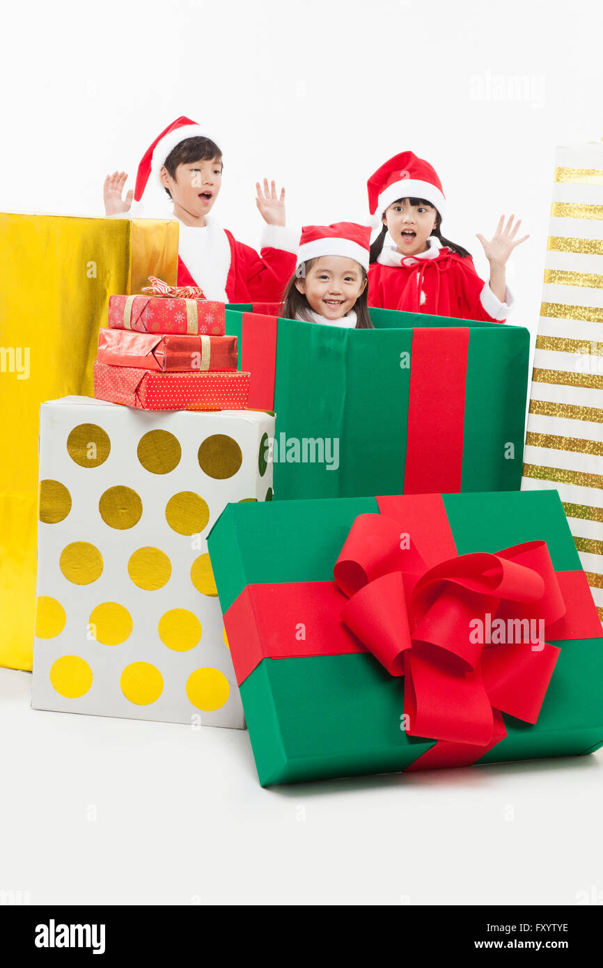 Porträt von drei Kindern in Santas Kleidung mit Geschenkkartons Stockfoto
