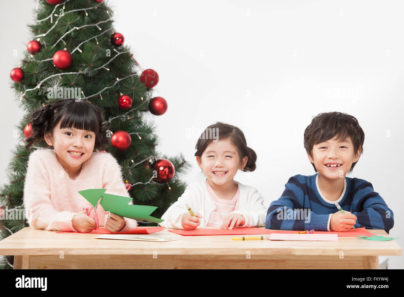 Porträt von drei lächelnden Kindern machen Papier Weihnachtsbaum starrte auf Vorderseite Stockfoto