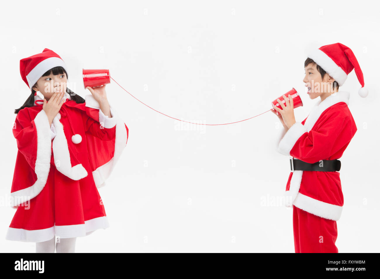 Jungen und Mädchen in Santas Kleidung spielen mit Schnur-Telefone Stockfoto