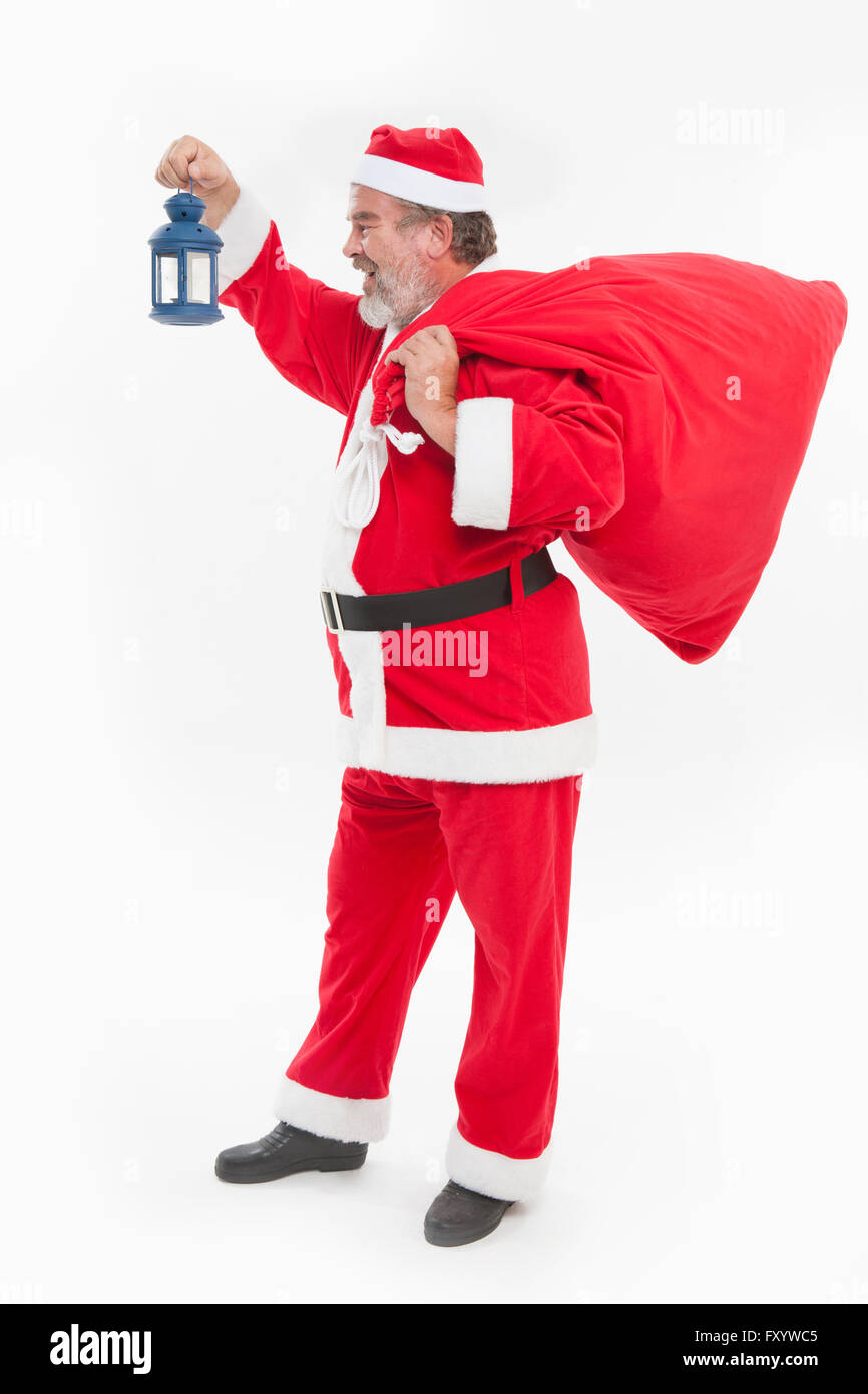 Seitenansicht des Lächelns Santa stehend mit einer Laterne und vorliegenden Tasche Stockfoto