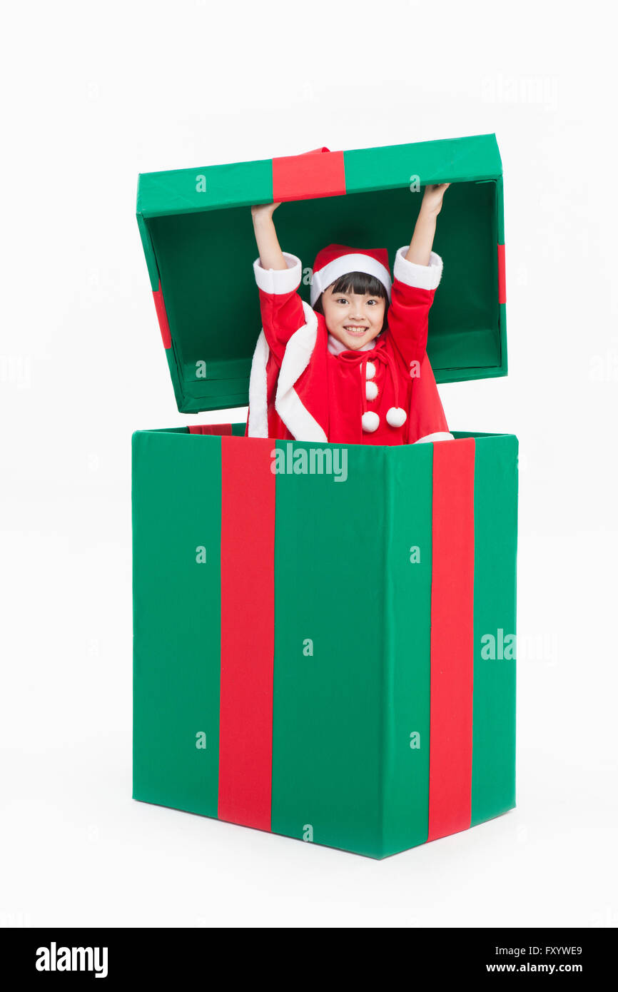 Porträt der lächelnde Mädchen in Santas Kleidung in eine große Geschenkbox starrte auf Vorderseite Stockfoto