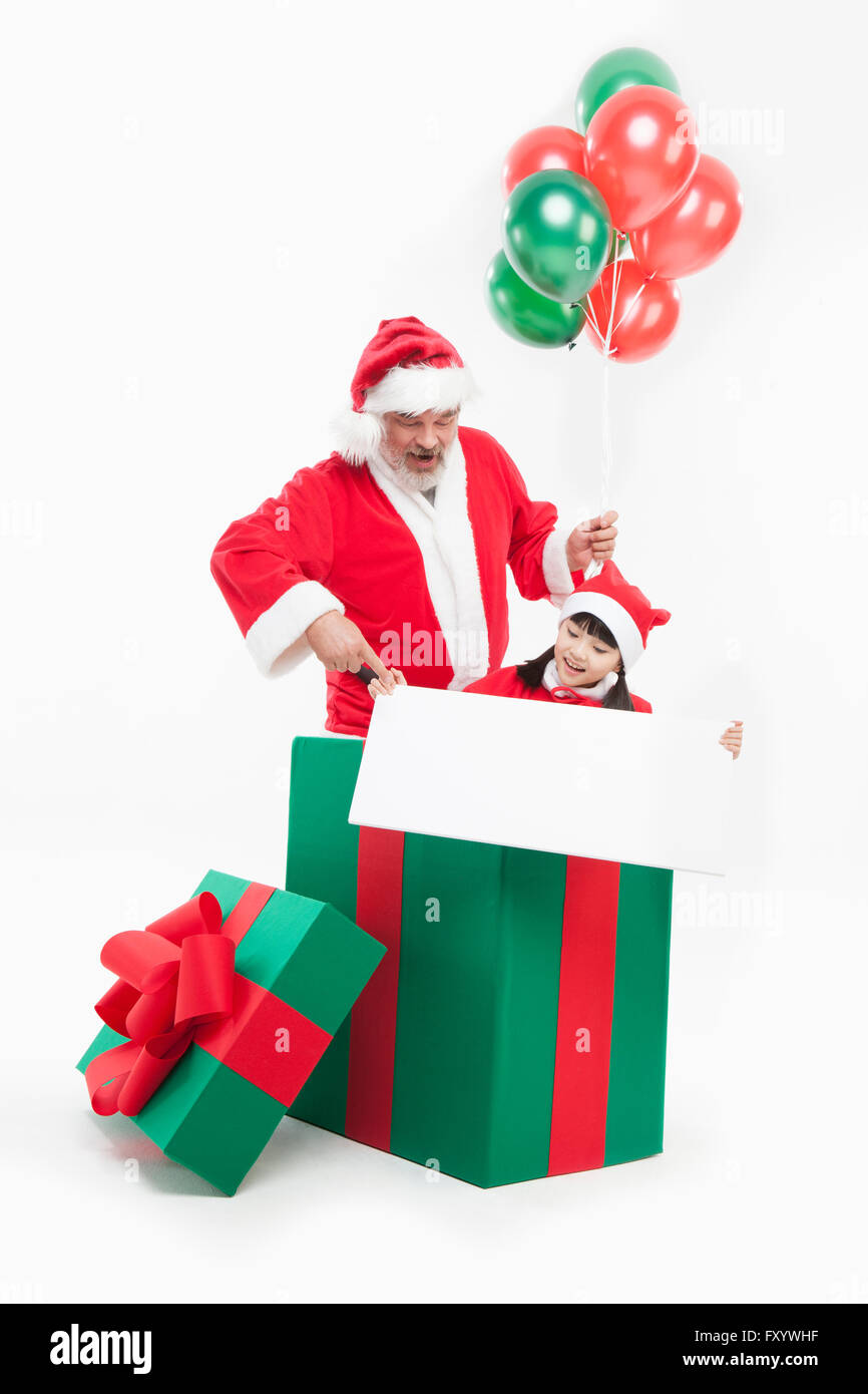 Porträt von lächelnden Weihnachtsmann und Mädchen mit Luftballons und Banner in eine große Geschenkbox Stockfoto