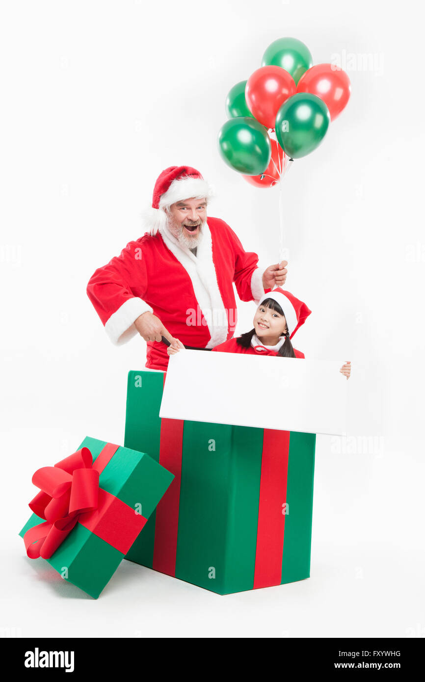 Porträt von lächelnden Weihnachtsmann und Mädchen mit Luftballons und Banner starrte vorne in einer großen Kiste vorhanden Stockfoto