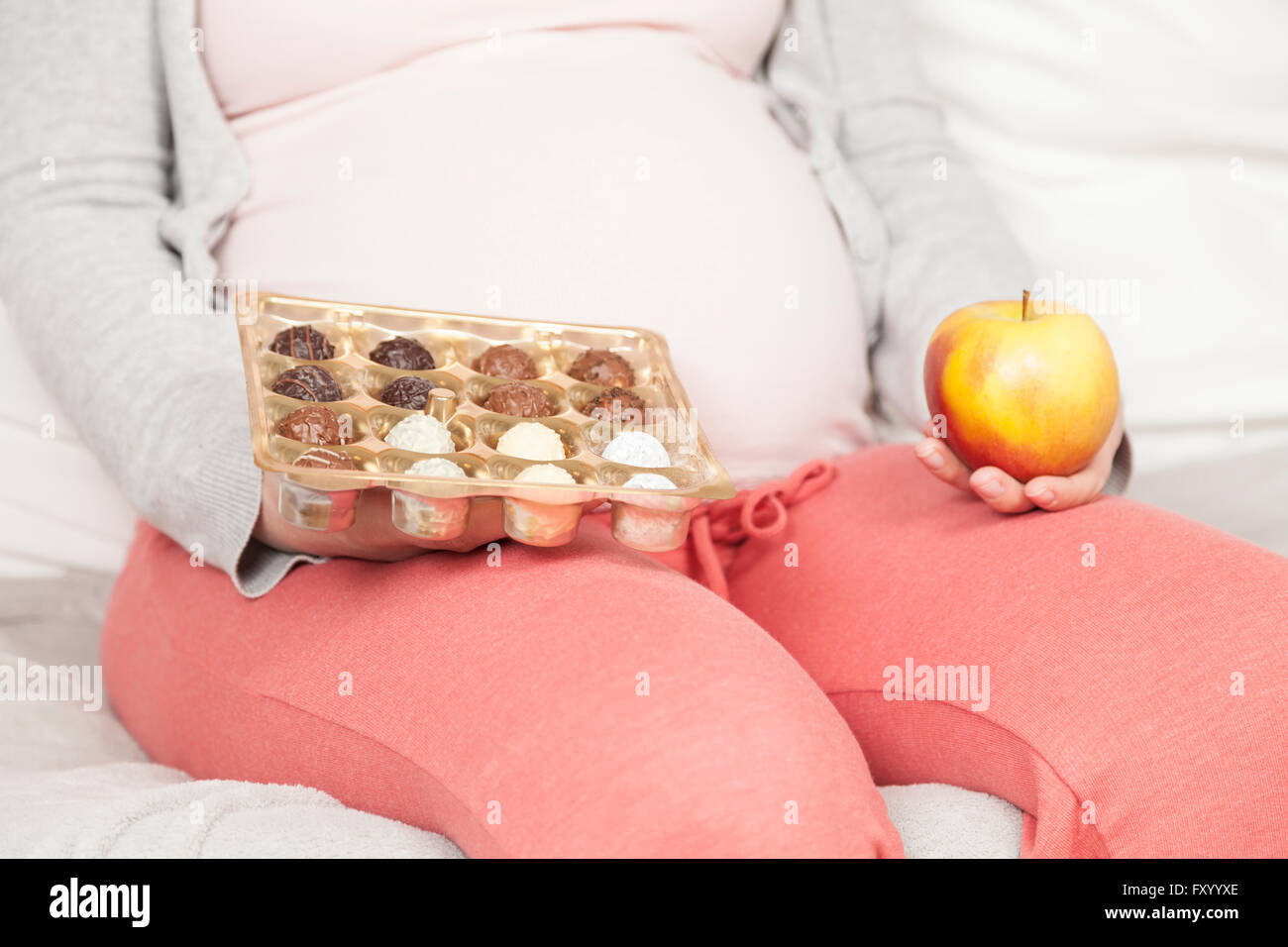 Schwangere Frau mit Apfel und Süßigkeiten Stockfoto