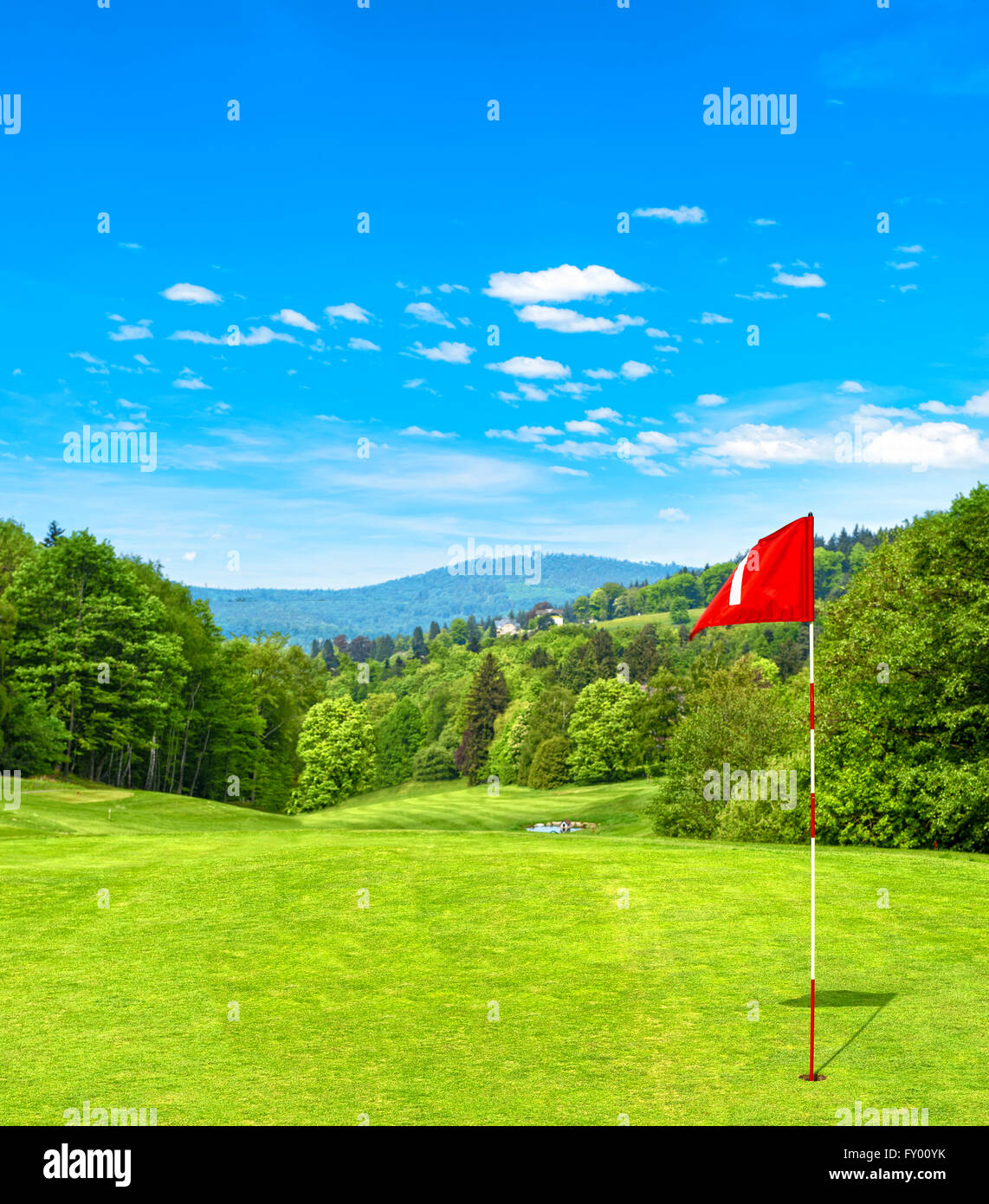 Grüne Golf Feld und blauer Himmel. Golfplatz mit roten Fahne. Frühlingslandschaft Stockfoto