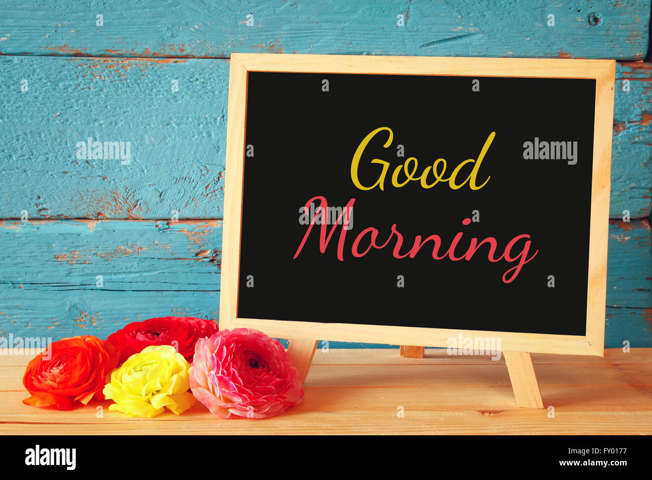 Tafel mit dem Ausdruck guten Morgen neben frischen Blumen darauf geschrieben. Stockfoto