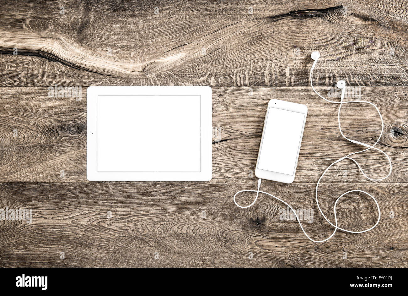 Digitale Geräte auf hölzernen Hintergrund. Smartphone mit Kopfhörer und Tablet-pc am Schreibtisch Stockfoto