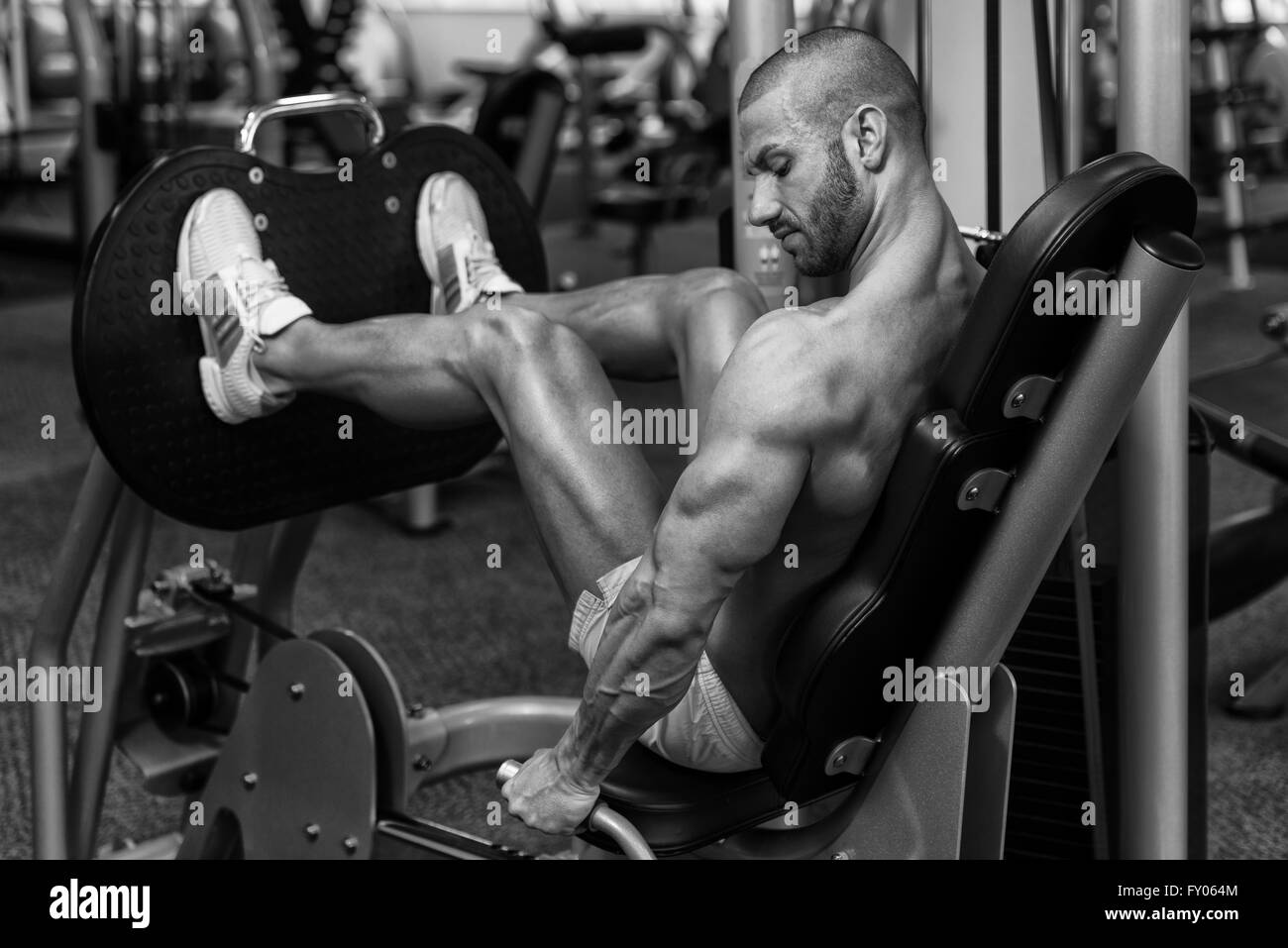 Attraktive junge Mann tut Beinpresse auf Maschine im Fitness-Studio Stockfoto