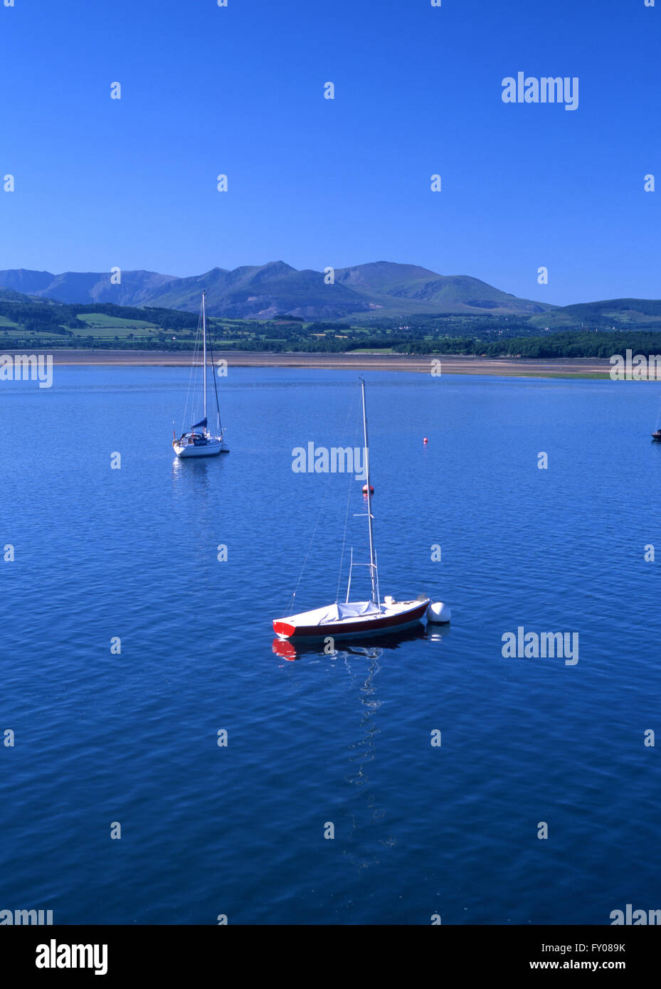 Blick über die Menai Strait von Beaumaris, Snowdonia auf sonnigen Sommermorgen mit Booten im Vordergrund North Wales UK Stockfoto
