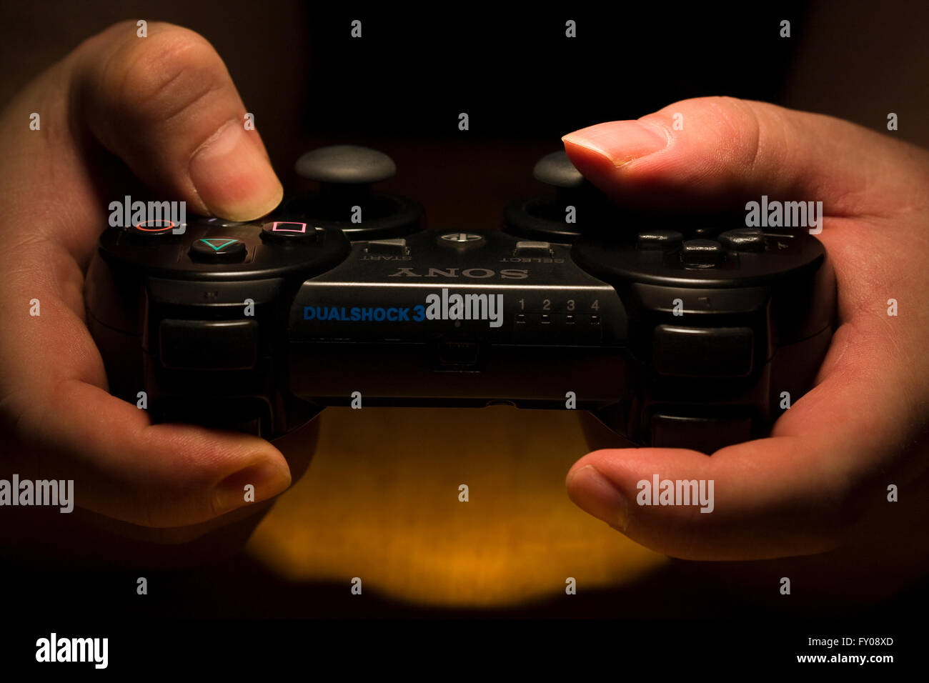 Zwei Hände halten ein drahtloses SONY Playstation Dual Shock 3 Controller, während der Daumen die Tasten drücken Stockfoto