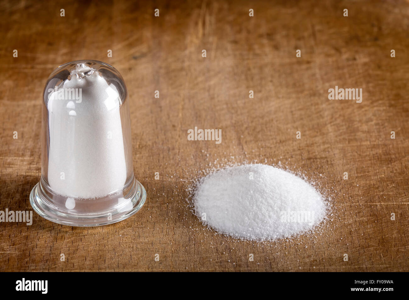 Salzstreuer Glas und verschüttetes Salz auf Holz Hintergrund Stockfoto