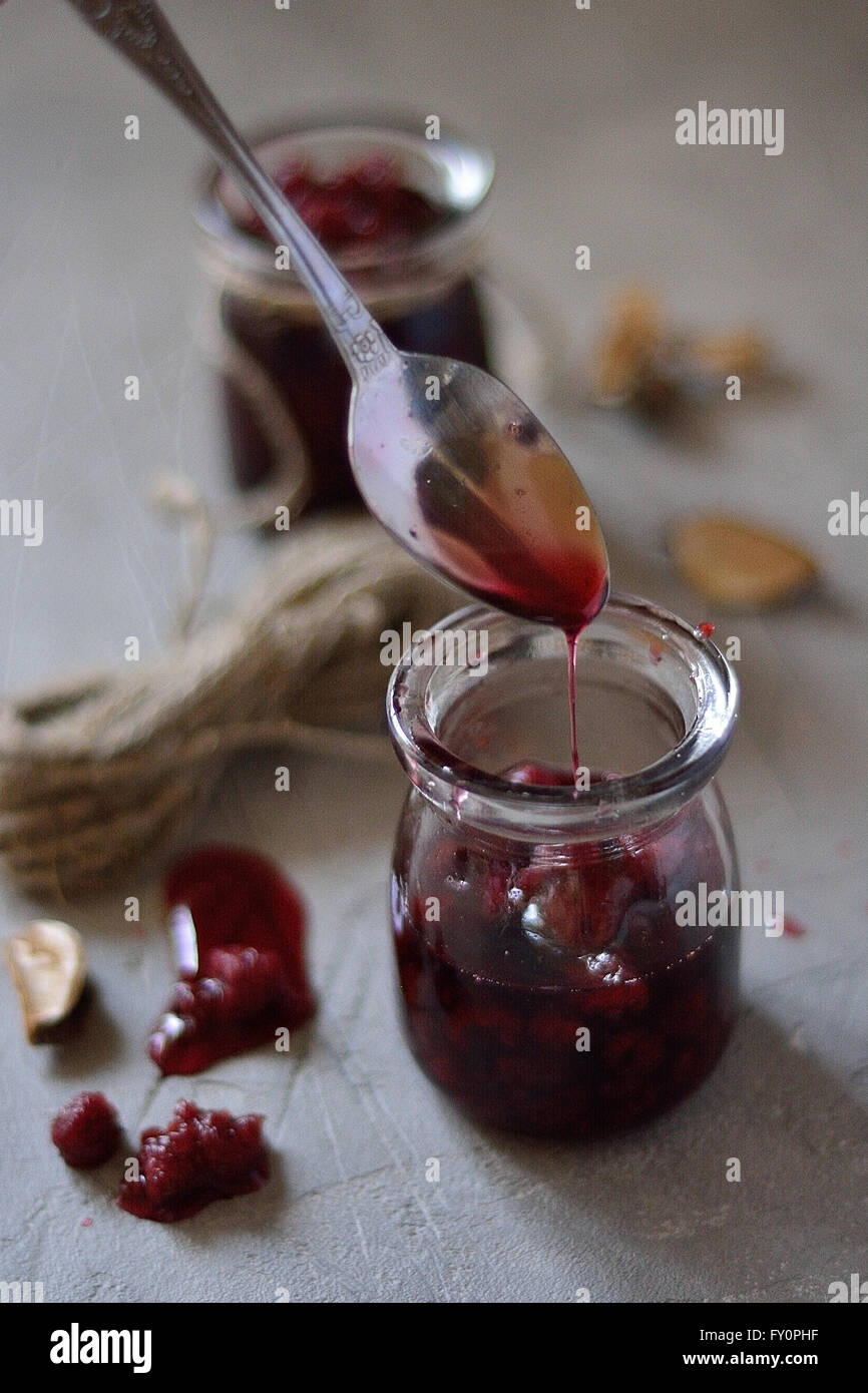 Himbeermarmelade tropft aus einem Löffel auf dem Tisch Stockfoto