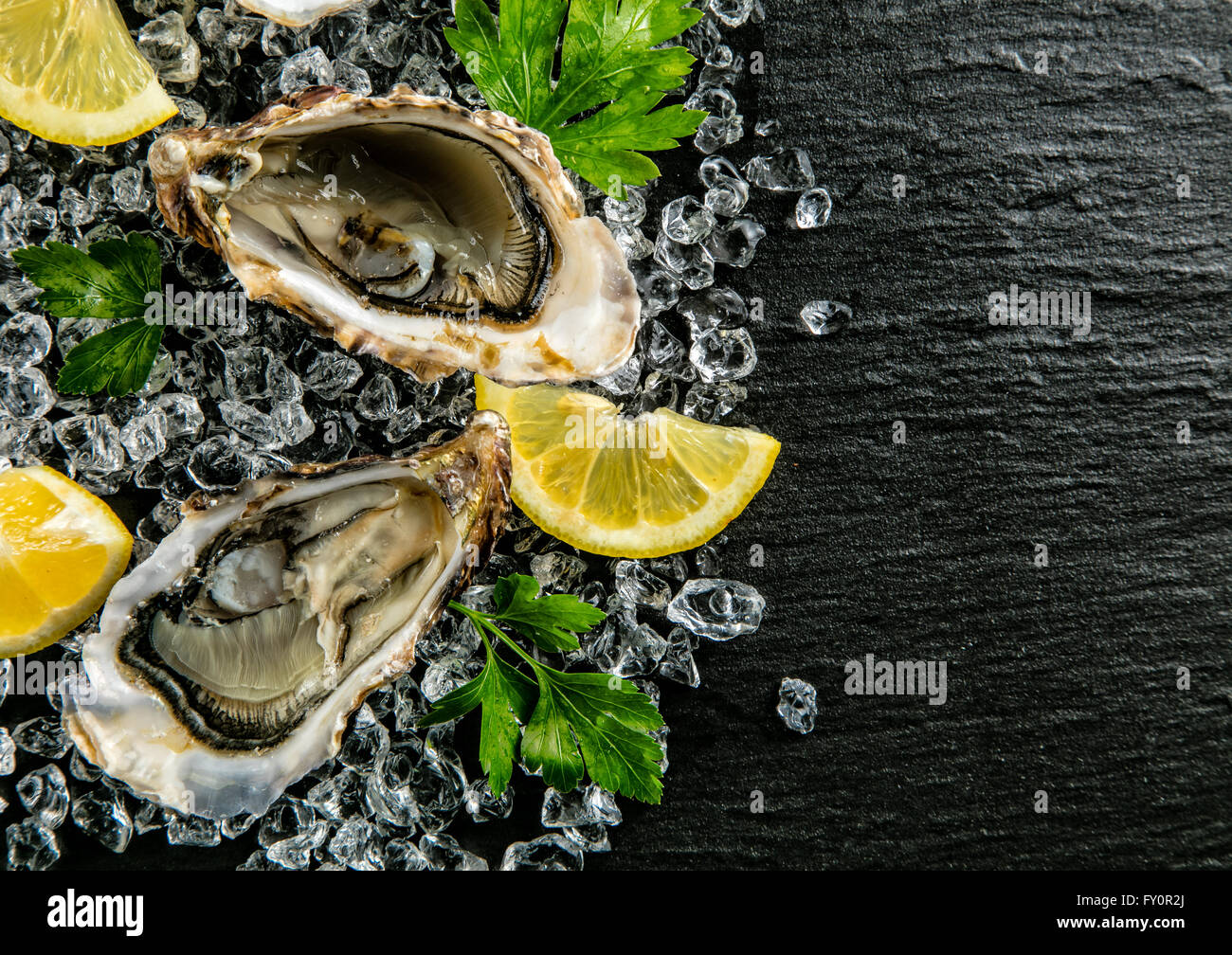 Austern auf Steinplatte serviert mit Eisgang Stockfoto