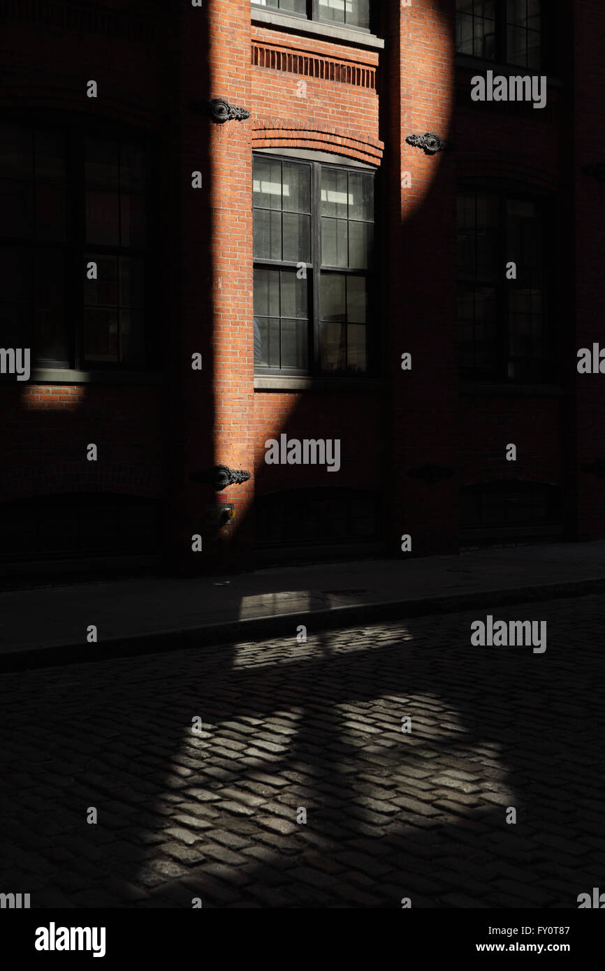 Sonnenstrahl trifft ein Backsteingebäude in einer DUMBO-Straße in Brooklyn Stockfoto