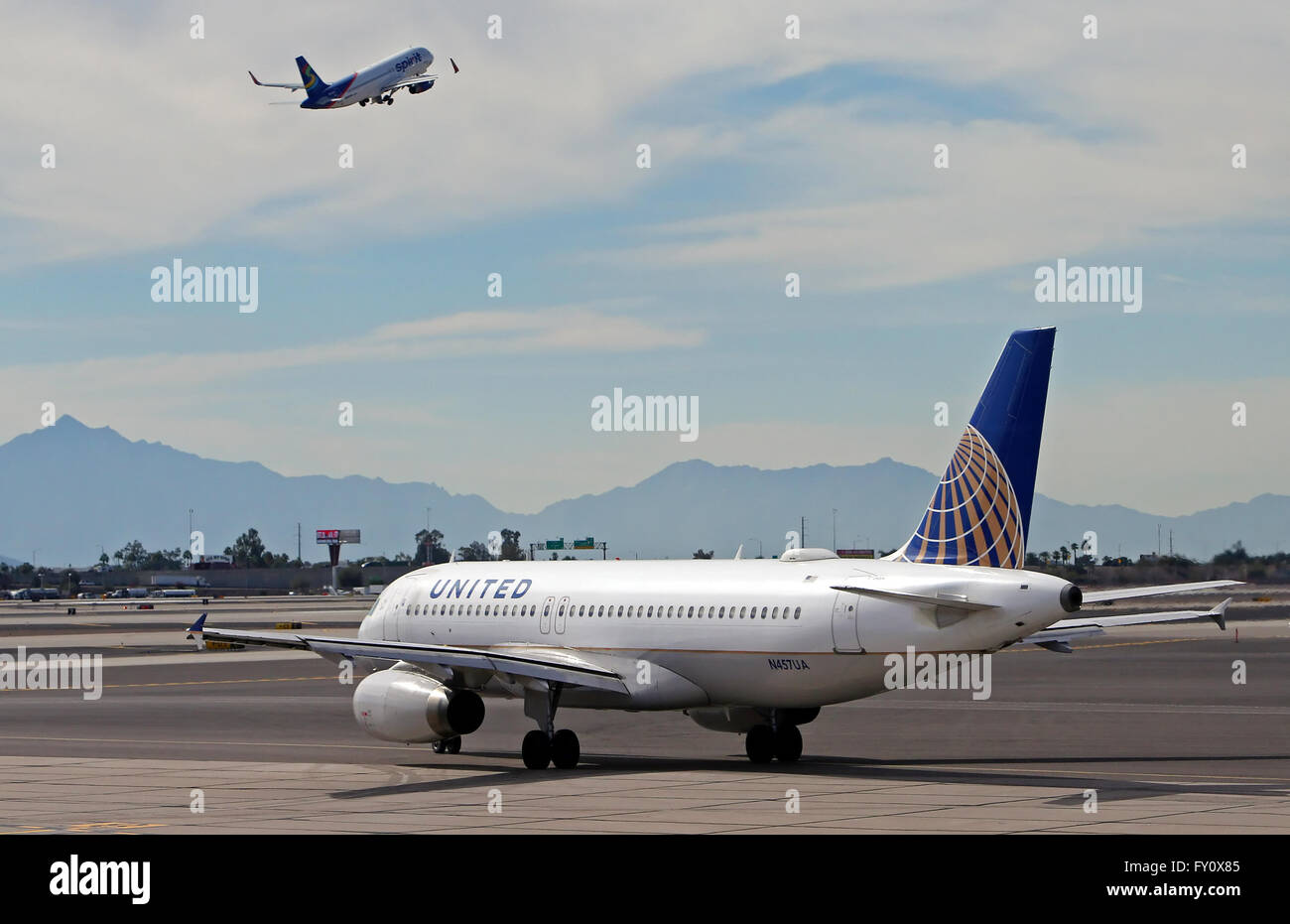 United Airlines Airbus A320 taxis als ein Spirit Airlines A320 bei Phoenix Sky Harbor International Airport hebt ab Stockfoto