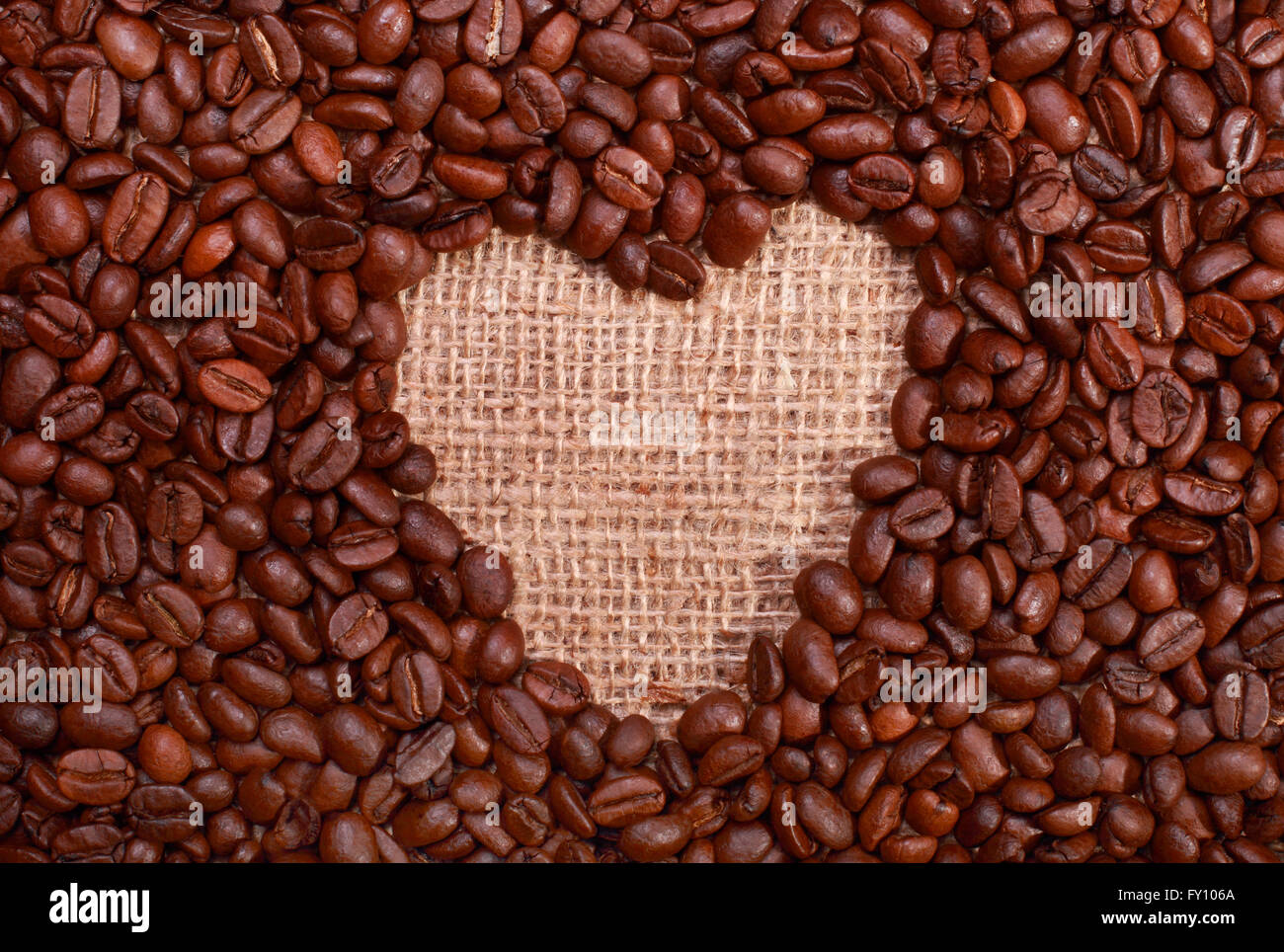 Gerösteter Kaffeebohnen mit textfreiraum in Form von einem Herz-Symbol für Liebe Kaffee auf Sackleinen Hintergrund Stockfoto