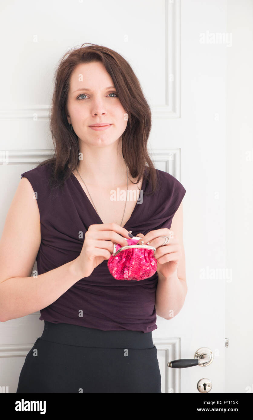 Porträt der Frau hält eine rote Geldbörse. Lebensstil-Bild der jungen Frau im schwarzen Kleid zeigt stolz, Zuversicht und Zufriedenheit. Stockfoto